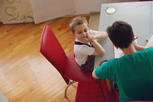 young mom woman doing home work with elementary school grade boy at home in kitchen