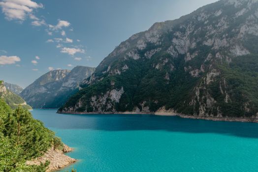 The concept of eco-tourism and active recreation. National Park. Mountain Emerald lake in the wooded mountains. Sunny day in autumn.