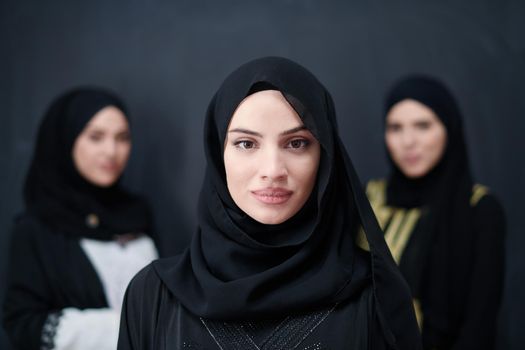 group portrait of beautiful muslim women in fashionable dress with hijab isolated on black chalkboard background representing modern islam fashion and ramadan kareem concept