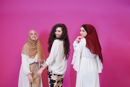 group portrait of beautiful muslim women two of them in fashionable dress with hijab isolated on pink background representing modern islam fashion and ramadan kareem concept