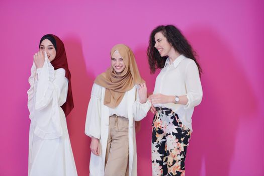 group portrait of beautiful muslim women two of them in fashionable dress with hijab isolated on pink background representing modern islam fashion and ramadan kareem concept