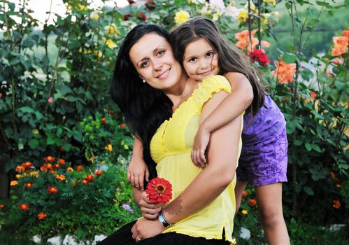 beautiful mom and daughter outdoor in garden  together with flower have fun and hug 