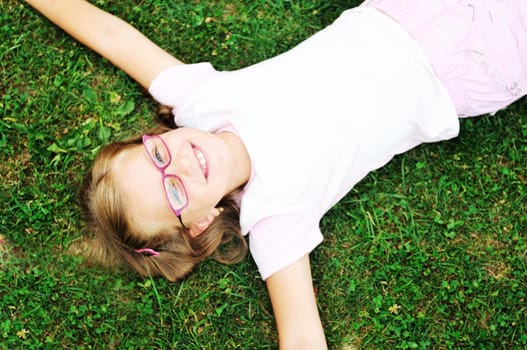 happy young girl children relax lie and have fun on grass with flower