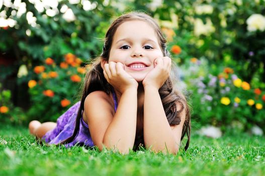 happy young girl children relax lie and have fun on grass with flower