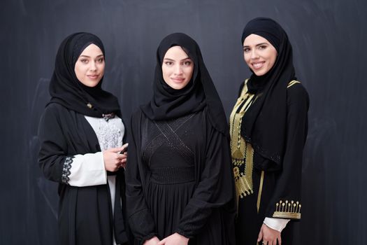 group portrait of beautiful muslim women in fashionable dress with hijab isolated on black chalkboard background representing modern islam fashion and ramadan kareem concept