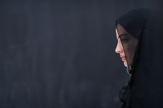 portrait of beautiful muslim woman in fashionable dress with hijab in front of black chalkboard representing modern islam fashion and ramadan kareem concept