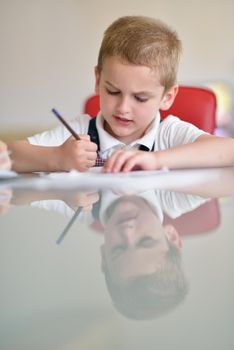 young mom woman doing home work with elementary school grade boy at home in kitchen