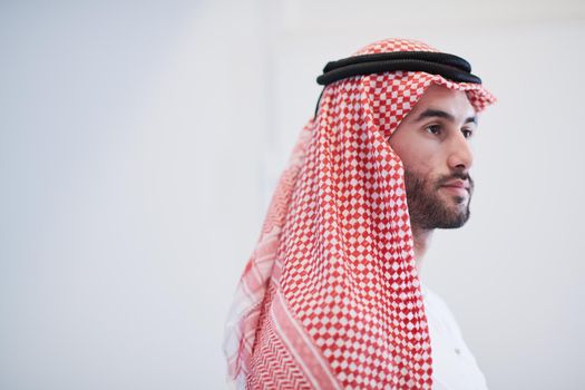 young modern muslim arabian businessman wearing traditional clothes while using smartphone at home