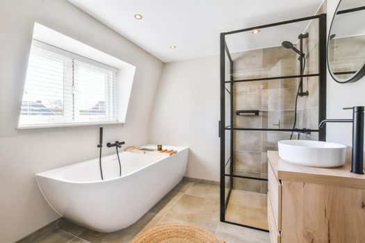 Delightful bathroom in a minimal style with a bathtub near the window