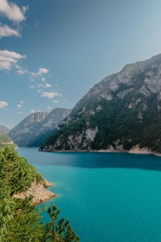 The concept of eco-tourism and active recreation. National Park. Mountain Emerald lake in the wooded mountains. Sunny day in autumn.