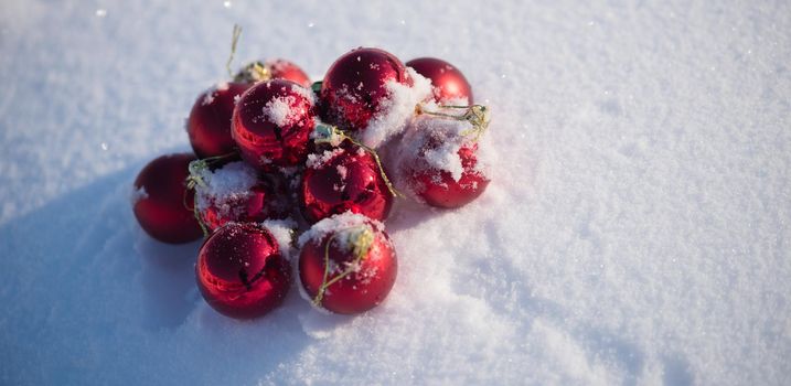 christmas red balls with long shadows  in fresh snow on beautiful sunny winter day