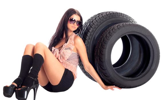 Young sexy girl lying near the car wheel and disk, isolated on white.