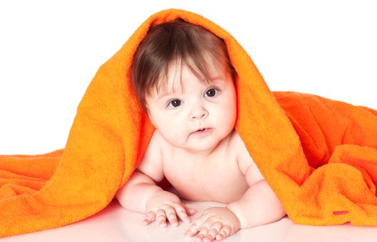 Portrait shot of a cute 6 months young baby lying under orange towel. Isolated on white.