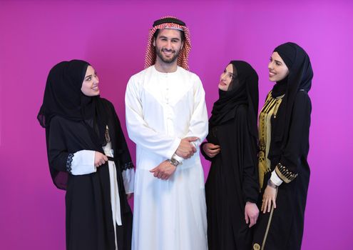 group portrait of young muslim people arabian man with three muslim women in fashionable dress with hijab isolated on pink background representing modern islam fashion and ramadan kareem concept