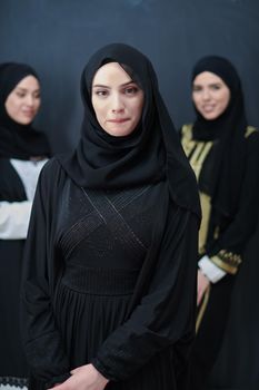 Portrait of Arab women wearing traditional clothes or abaya. Young muslim girls posing in front of black chalkboard representing islamic arabic fashion and ramadan kareem concept