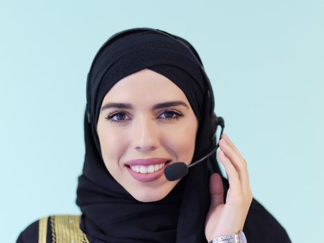 portrait of muslim female with hijab scarf customer representative business woman with phone headset helping and supporting online with customer in modern call centre isolated on cyan background