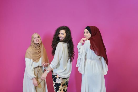 Young muslim women posing on pink background. Happy and pretty girls two wearing hijab representing Ramadan concept