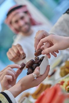 Muslim family having iftar together during Ramadan. Arabian people gathering for traditional dinner during fasting month. Dates sharing to break fasting