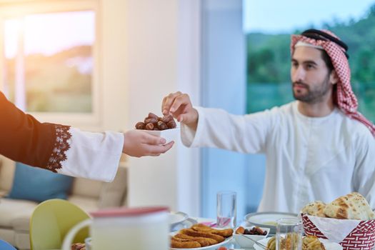 Muslim couple sharing dates for starting iftar. Arabian woman serving bowl with dates to man for breaking fast during Ramadan.