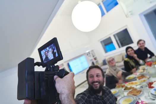 Professional videograph recording video while Muslim family having iftar together during Ramadan. Arabian people gathering for traditional dinner during fasting month.