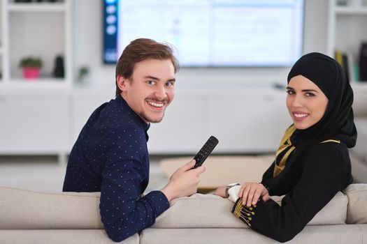 Young muslim couple enjoing time together at home during Ramadan. Happy arabic family watching TV