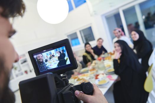 Professional videograph recording video while Muslim family having iftar together during Ramadan. Arabian people gathering for traditional dinner during fasting month.