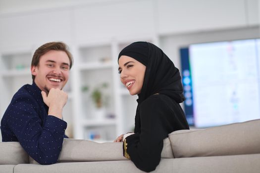 Young muslim couple enjoing time together at home during Ramadan. Happy arabic family watching TV