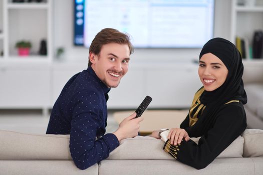 Young muslim couple enjoing time together at home during Ramadan. Happy arabic family watching TV