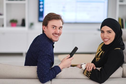 Young muslim couple enjoing time together at home during Ramadan. Happy arabic family watching TV