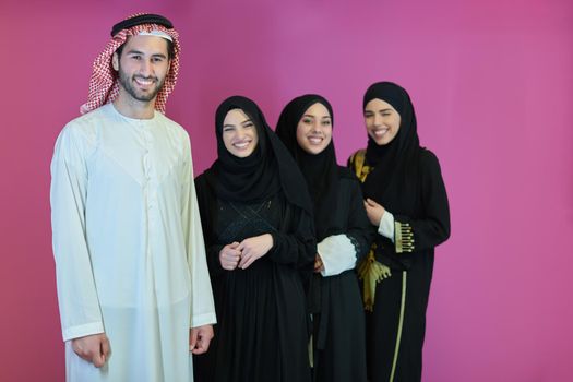 Portrait of young muslim people in traditional clothes. Happy arabic family together, man and three women isolated on pink background