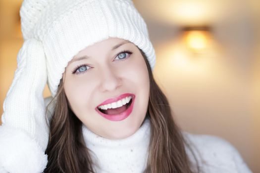 Christmas, people and winter holiday concept. Happy smiling woman wearing white knitted hat as closeup face xmas portrait.