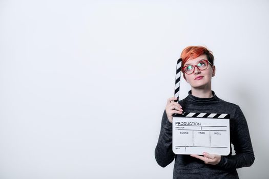 redhead woman on white background holding movie clapper cinema concept