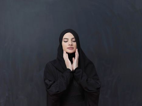 Portrait of young Muslim woman making dua. Arabian girl wearing abaya keeps hands in praying gesture. Representing worship to God and Ramadan Kareem concept