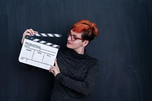 redhead woman on black chalkboard holding movie clapper cinema concept