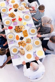 top view of modern multiethnic muslim family waiting for the beginning of iftar dinner during a ramadan feast at home