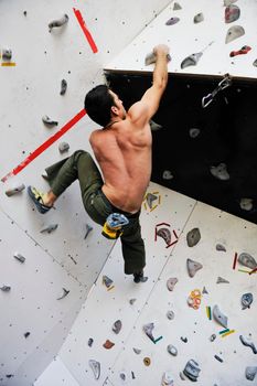 young and fit man exercise free mountain climbing on indoor practice wall