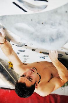 young and fit man exercise free mountain climbing on indoor practice wall