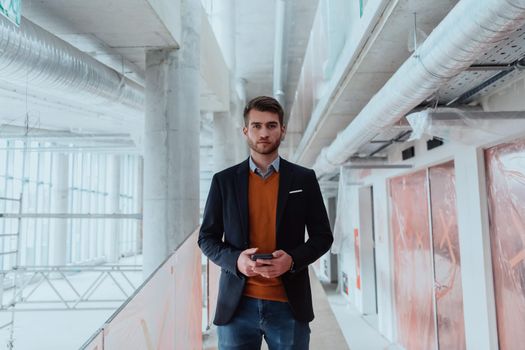 businessman architect expert using a smartphone while overseeing the construction site of a modern office building