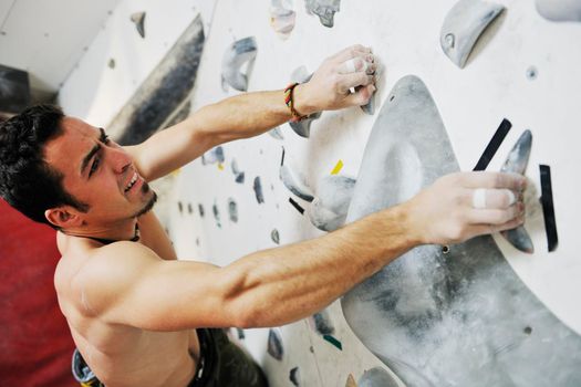 young and fit man exercise free mountain climbing on indoor practice wall