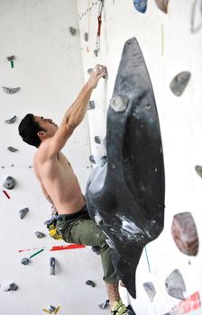 young and fit man exercise free mountain climbing on indoor practice wall