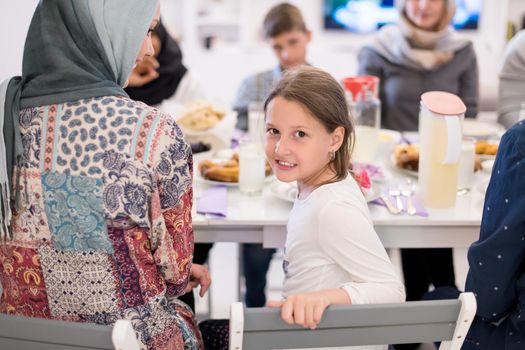 cute little girl enjoying iftar dinner together with modern multiethnic muslim family in the background  during a ramadan feast at home