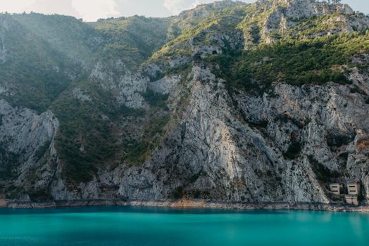 The concept of eco-tourism and active recreation. National Park. Mountain Emerald lake in the wooded mountains. Sunny day in autumn.