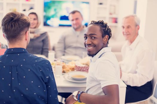 african american man enjoying iftar dinner together with modern multiethnic muslim family during a ramadan feast at home