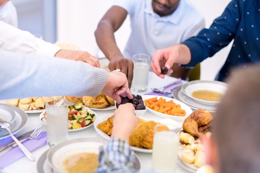 modern multiethnic muslim family sharing a bowl of dates while enjoying iftar dinner together during a ramadan feast at home