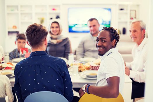 african american man enjoying iftar dinner together with modern multiethnic muslim family during a ramadan feast at home