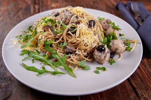 Spaghetti with meatballs and tomato sauce, italian pasta with olives and arugula