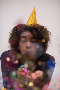 happy young woman celebrating new years eve party while blowing confetti