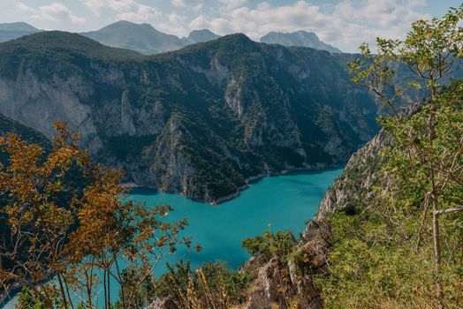 The concept of eco-tourism and active recreation. National Park. Mountain Emerald lake in the wooded mountains. Sunny day in autumn.