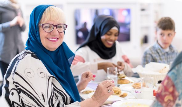 modern muslim grandmother enjoying iftar dinner together with multiethnic family during a ramadan feast at home