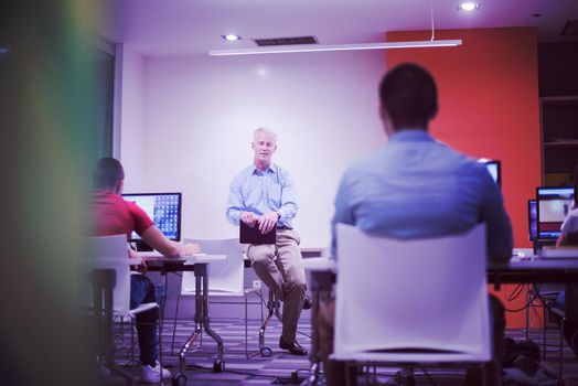 handsome mature teacher and students in computer lab classroom